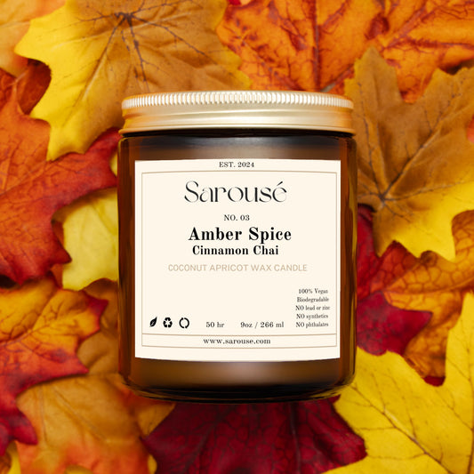 A jar candle labeled Sarouse’e No. 01 Warm Haven Cashmere Vanilla, placed on a bed of colorful autumn leaves.