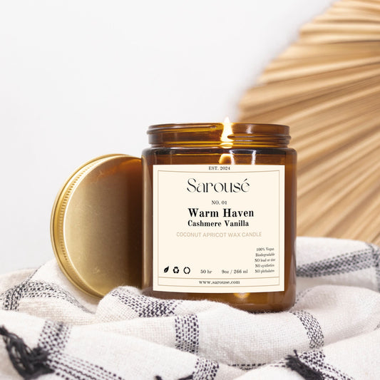 Brown candle jar labeled 'Fraser Fir' on a white and black checkered cloth with a wooden surface in the background.